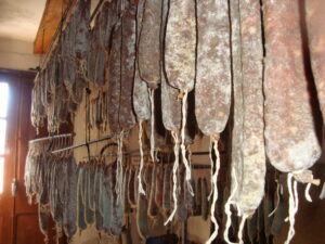 Xolís_curación_en_bodega‘Xolís’ del Pirineo, el embutido que se prepara con las partes nobles del cerdo Cal Tomàs, en La Pobla de Segur, es uno de los productores de un salchichón que se prepara con jamón, paletilla, lomo, un poco de tocino para dar jugosidad y un sencillo adobo de sal y pimienta. Teniendo en cuenta que los embutidos; a diferencia de los salazones como la cecina o el jamón, han sido históricamente una manera de conservar gran cantidad de grasa, sangre, manteca y otras partes menos refinadas -pero bien sabrosas, sobre todo una vez especiadas- del cerdo, el xolís del Pirineu es, de partida, un caso especial. Este salchichón curado, tradicional del Pallars Jussà y del Pallars Sobirà, en Lleida, está pensado para comer tal cual o acompañado con pan —aunque hay quien cocina con él, como veremos más adelante. “Nace de la voluntad de conservación, durante las matanzas de invierno, de algunas de las partes más nobles del cerdo”, nos cuentan Laura y Miquel Gordó, cuarta generación de carniceros de Cal Tomàs, uno de sus elaboradores estrella en La Pobla de Segur.