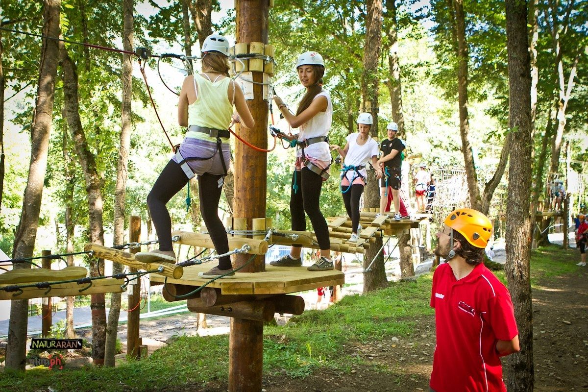 Descubre el emocionante Parque de Aventuras Naturaran en el Val d’Aran: ¡Aventura entre árboles! ¿Buscas un plan emocionante para disfrutar en familia o con amigos?' ¡No busques más! En el bonito pueblo de Les, en la Val d'Aran, a 20 minutos de Vielha,te espera nuestro increíble Parque de Aventuras Naturaran. Diseñado para todas las edades y niveles de habilidad. Nuestro parque cuenta con una amplia gama de opciones para que todos puedan tener su propia dosis de adrenalina! Los más pequeños de la casa pueden disfrutar de nuestro Circuito Infantil especialmente diseñado, equipado con medidas de seguridad pasiva para su tranquilidad y protección. Si eres un aventurero experimentado, nuestros 4 circuitos multiaventura te desafiarán y te brindarán una experiencia emocionante. Supera obstáculos, prueba tu equilibrio y siente la emoción mientras te mueves entre las copas de los árboles. ¡La diversión está garantizada! Pero eso no es todo. Para aquellos que buscan una experiencia aún más emocionante, ofrecemos un circuito de tirolinas que te hará volar por el aire. Imagina la sensación de libertad mientras surcas los cielos y admiras la impresionante belleza natural que te rodea. Y para los amantes de las emociones fuertes, contamos con una tirolina gigante de 250 metros que te dejará sin aliento. En nuestro Parque de Aventuras Naturaran del Val d'Aran, la seguridad es nuestra máxima prioridad. Contamos con un equipo de profesionales altamente capacitados que supervisan constantemente las instalaciones y se aseguran de que todos los visitantes estén protegidos en todo momento. Así que no pierdas la oportunidad de disfrutar de un magnífico día en familia o con amigos en nuestro Parque de Aventuras del Val d'Aran. ¡Ven y únete a la diversión! ¡Te esperamos con los brazos abiertos para vivir una experiencia inolvidable en medio de la naturaleza! Detalles de la actividad CIRCUITO INFANTIL para niños menores de 9 años o con menos de 135 cm de altura CIRCUITO AMARILLO + TIROLINA GIGANTE: Personas con más de 135 cm de altura, menos de 195 cm y menos de 95 kg. 4 CIRCUITOS MULTIAVENTURA + TIROLINA GIGANTE: Personas con más de 155 cm de altura, menos de 195 cm y menos de 95 kg. 4 CIRCUITOS MULTIAVENTURA + CIRCUITO DE TIROLINAS + TIROLINA GIGANTE: Personas con más de 155 cm de altura, menos de 195 cm y menos de 95 kg. Del Abril a Junio, grupo mínimo 4 pax. Horario 10h30 De Julio a Septiembre abierto todos los días de 10h30 a 13h30 y 16h30 a 20h30